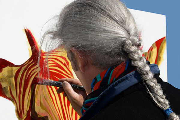 photo d'une femme qui peint et qui a des cheveux blancs tressés